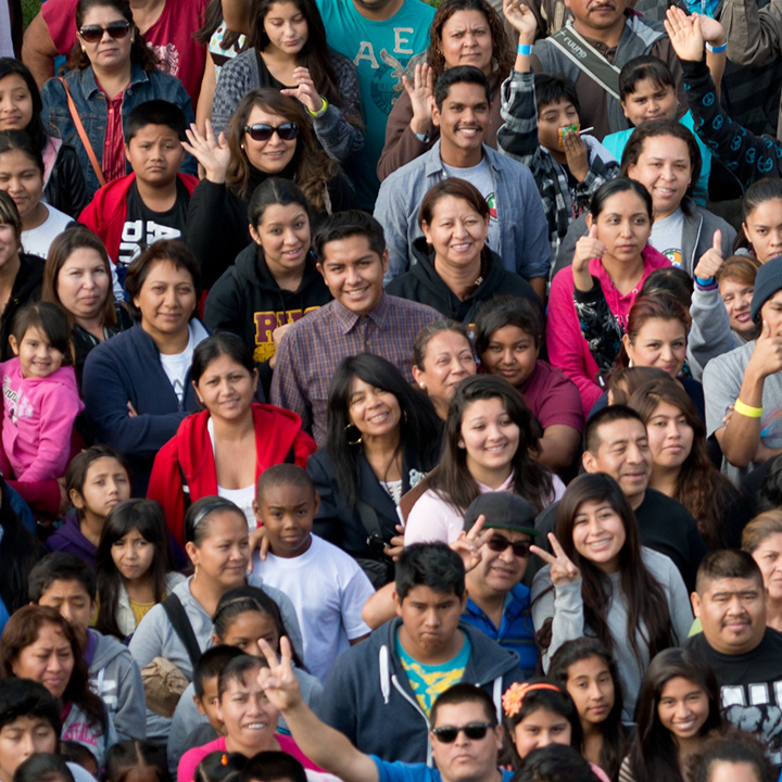 A large crowd of people looking up and smiling to the camera