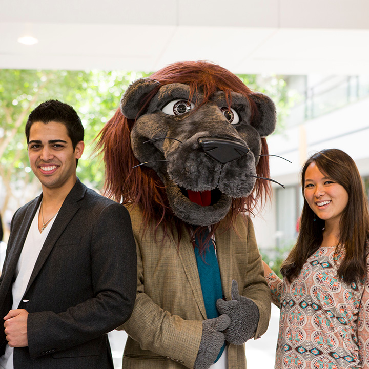 Two students standing with Iggy who is wearing professional attire