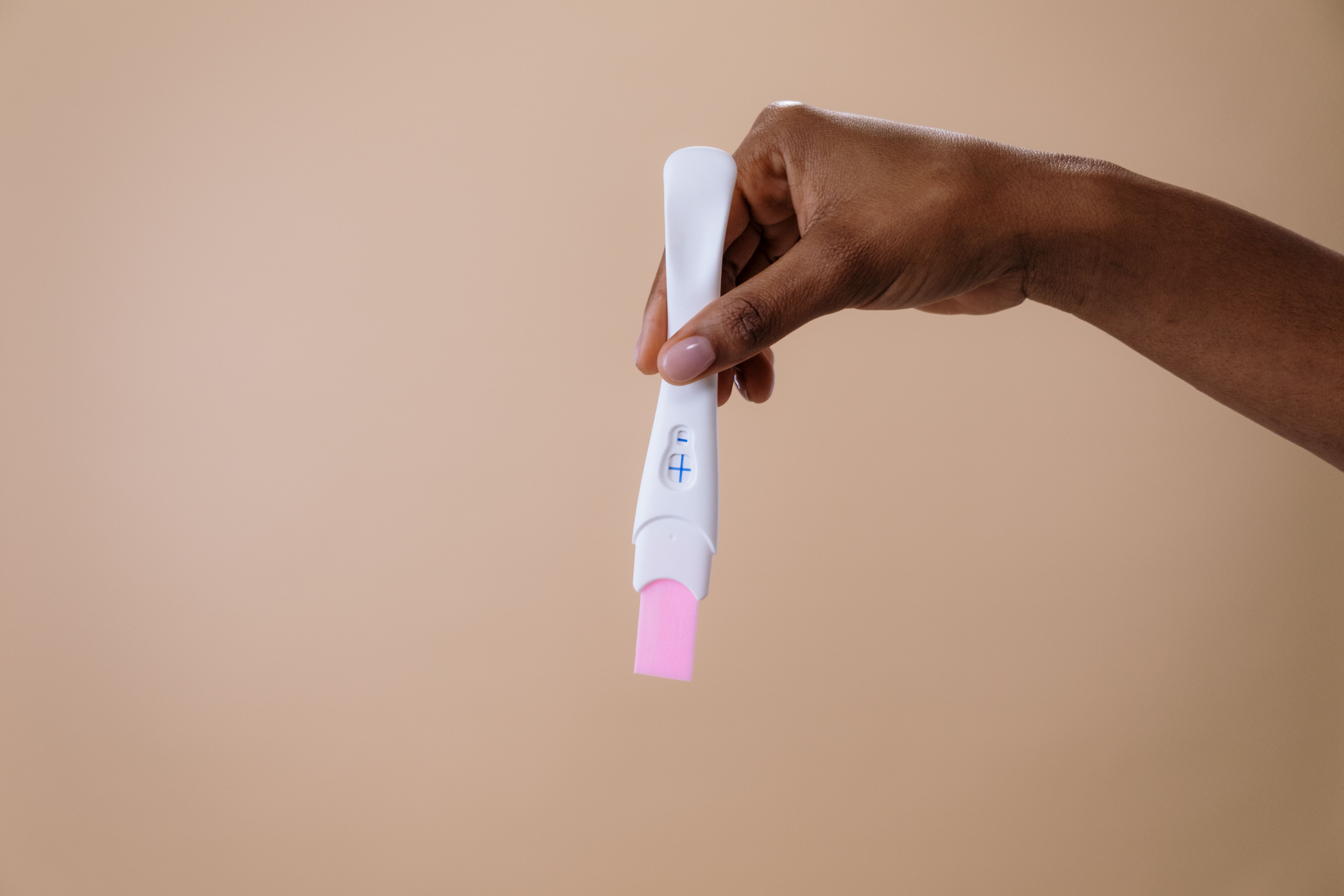 Woman holding pregnancy test strip representing fertility